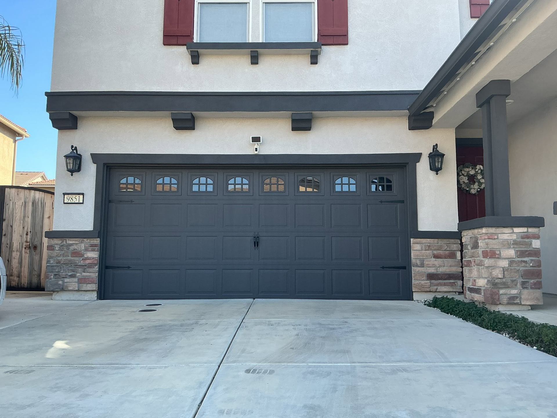 Custom black garage door and trim repaint on stucco home