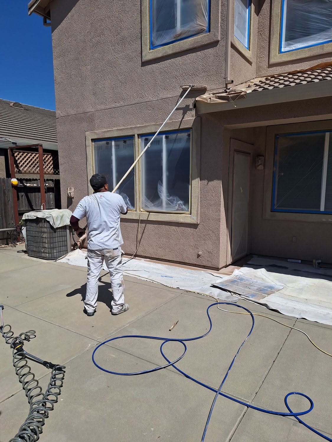 Crew masking and spraying a stucco exterior