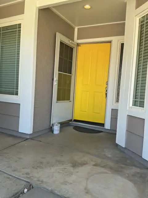 Bright yellow front door repaint with gray stucco entry