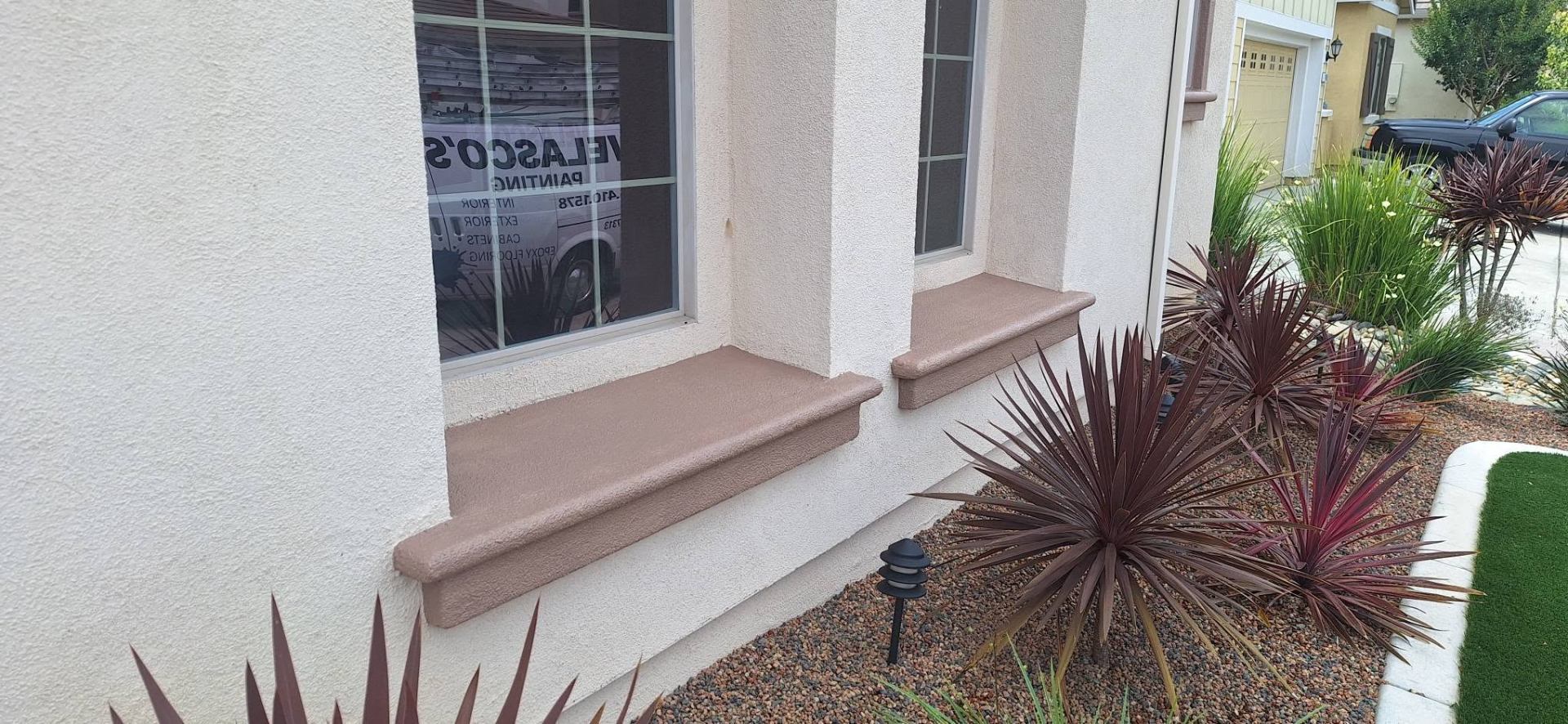 Freshly painted stucco window sills reflecting the Velasco's Painting van