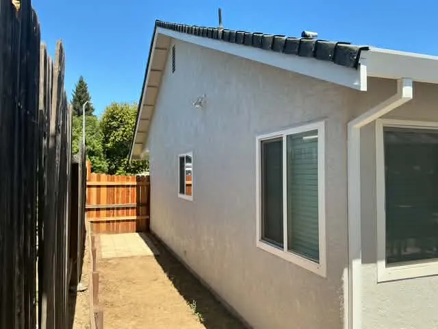 Gray stucco side elevation with white window trim