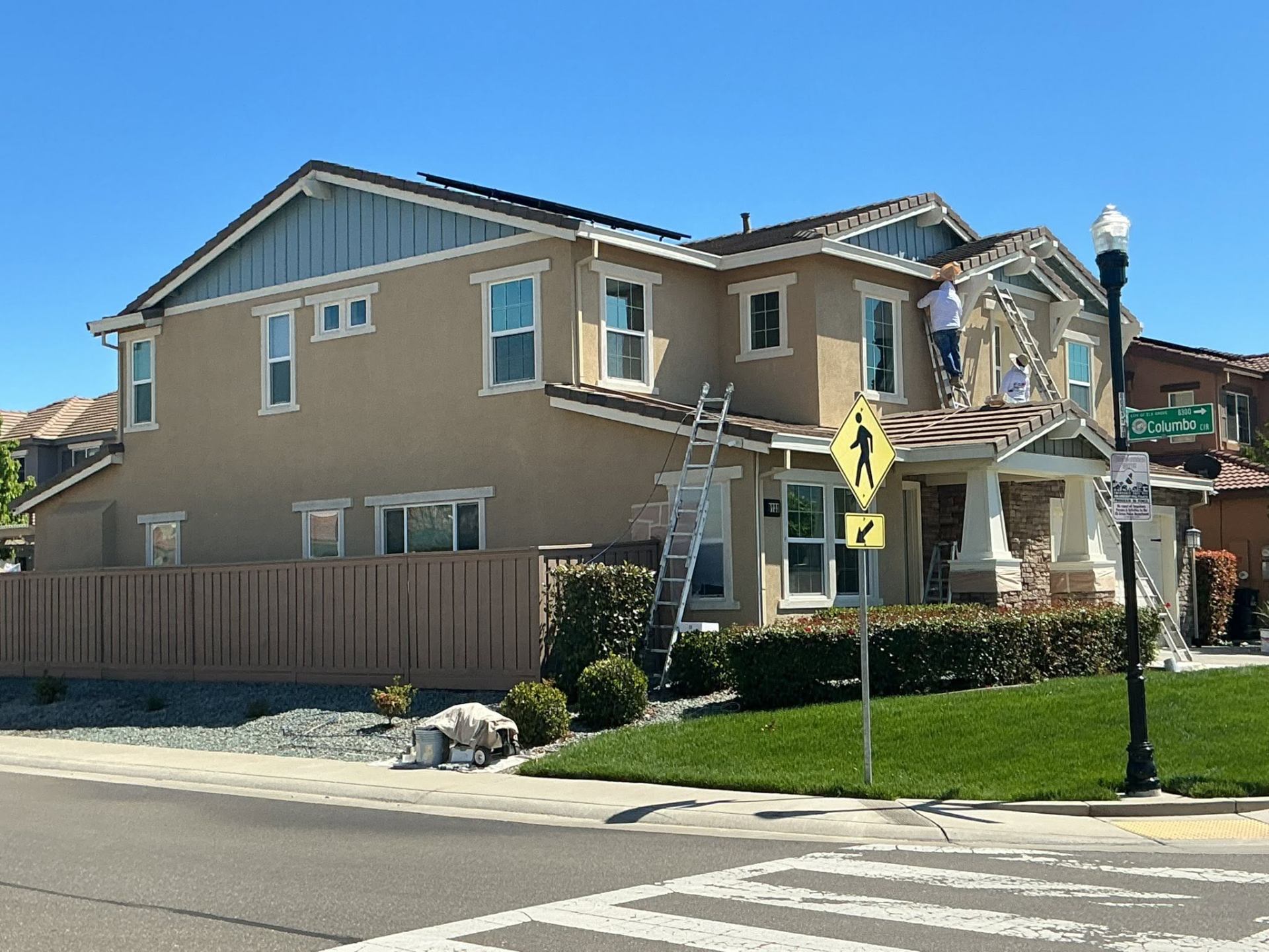 Velasco's crew on ladders painting a craftsman two-story